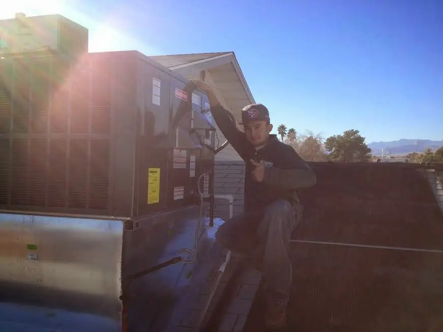 HVAC technician performing AC Tune-Up on a rooftop unit in Brawley